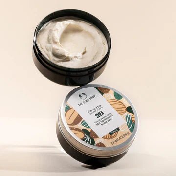 Two containers of The Body Shop's Shea body butter, one is an open container showing the body butter inside and the other one has the lid on showing the label.