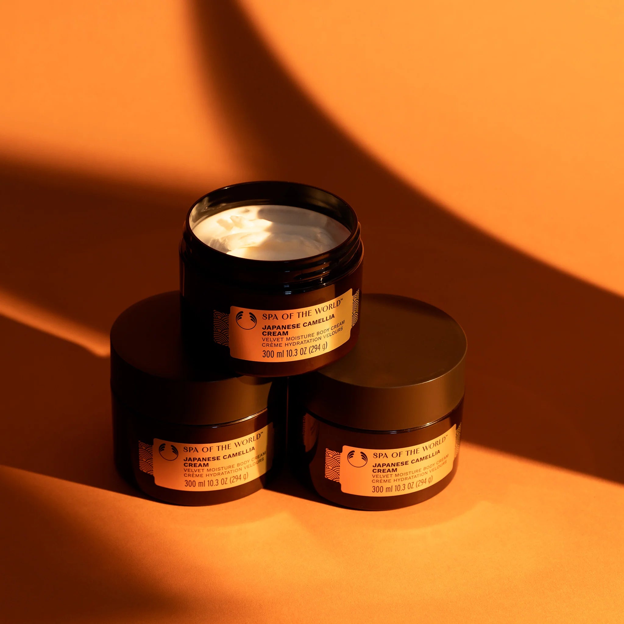 Three jars of The Body Shop's Spa of the World Japanese Camellia Cream with one of the jars open to show the cream inside