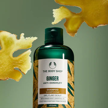 The Body Shop's Ginger shampoo bottle with ginger slices around it on a green background